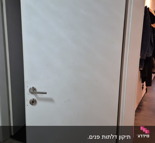 דלת לבנה עם ידית מתכת בחדר פנימי